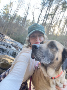 A girl and a shelter dog enjoy a daycation hike together, walking along a trail outdoors while spending quality time and exploring nature.